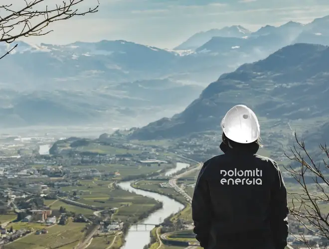 Tecnico Dolomiti Energia con elmetto osserva il panorama della Valle dell'Adige e le Dolomiti