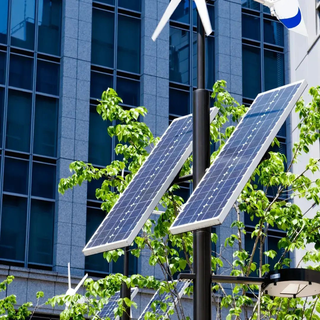 Palo con pannelli solari e mini turbina eolica in ambiente urbano con edificio moderno