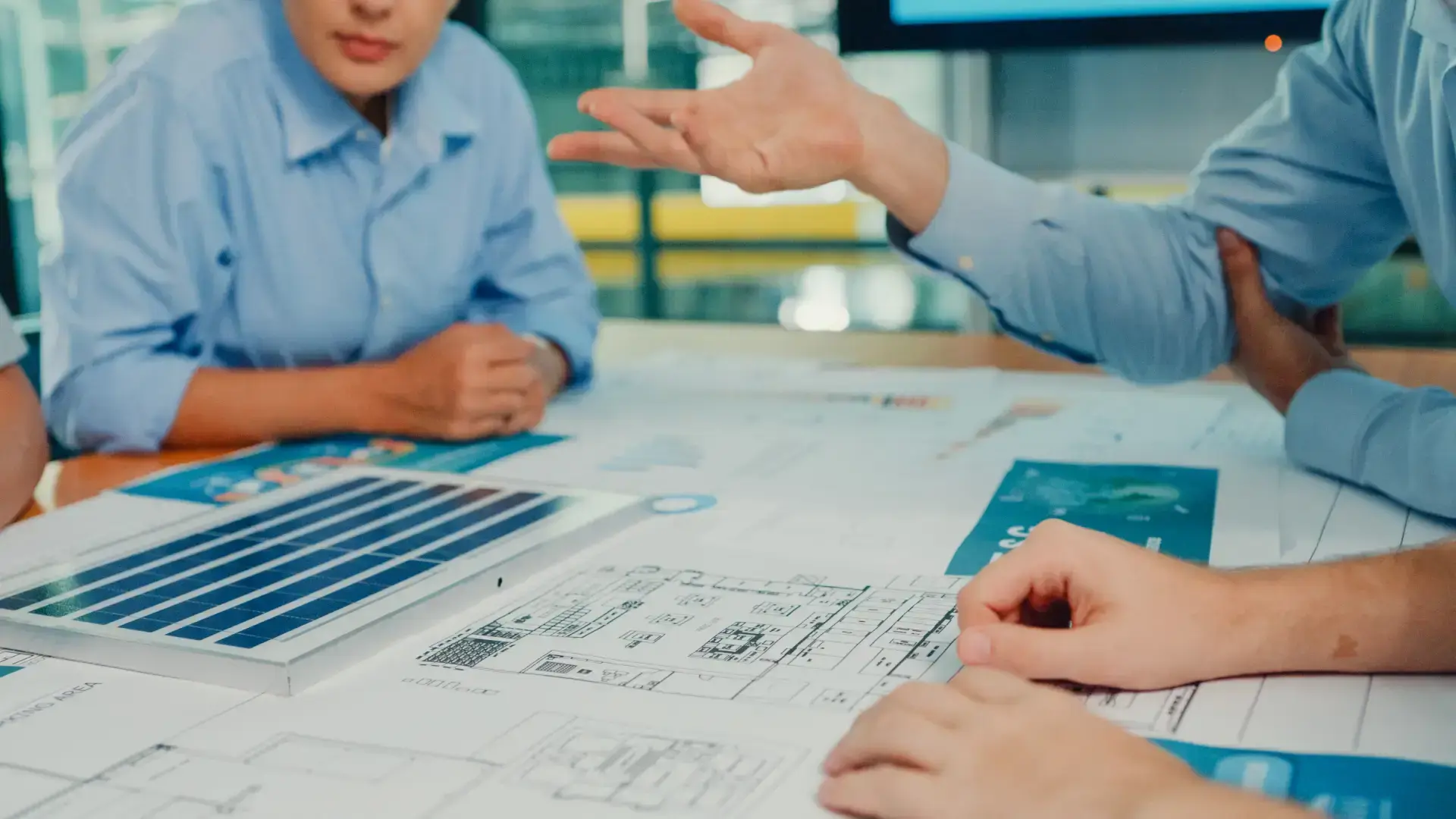 Team di professionisti che discute su planimetrie e documenti tecnici durante riunione