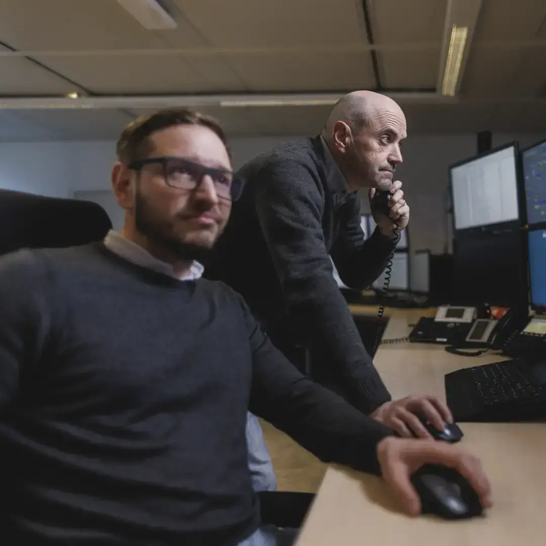 Due operatori in sala controllo che gestiscono impianti energetici da remoto